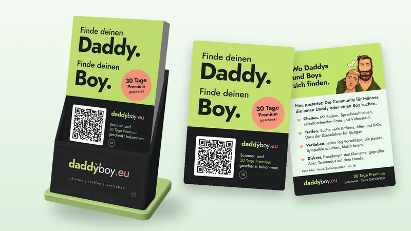 Zwarte kaarthouder met groene voet en een stapel kaartjes “Finde deinen Daddy. Finde deinen Boy.”, daarnaast het kaartje van voren en van achteren.